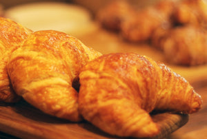 Croissants on a wooden board with a warm, blurred background